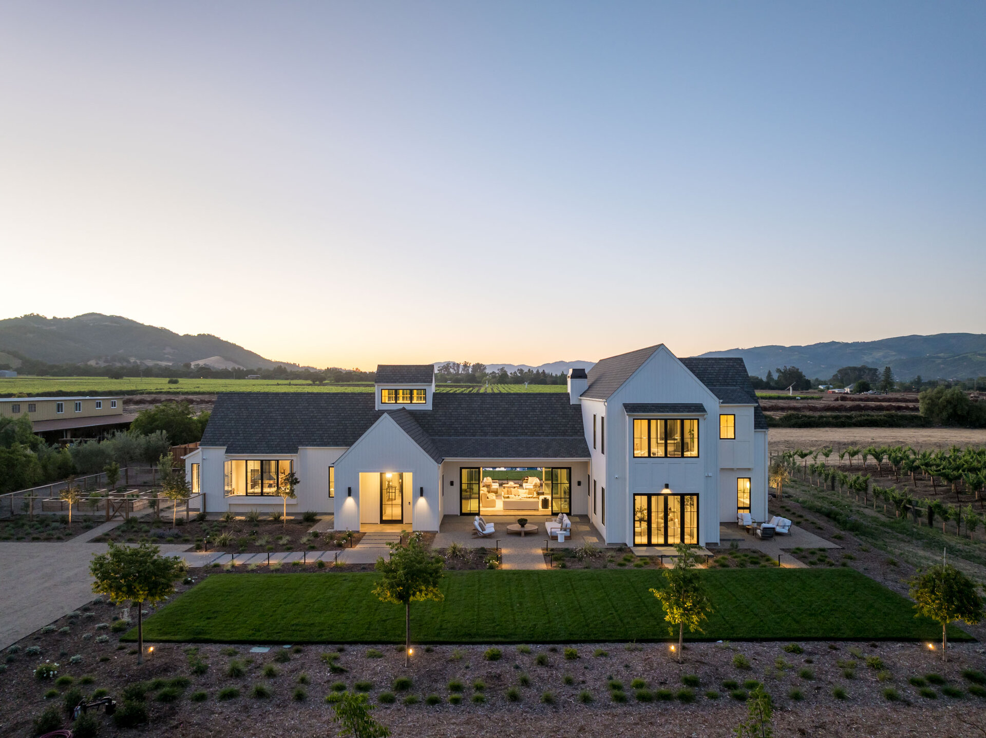 Aerial twilight view of the 1523 Sperring Road estate, glowing windows and vineyard hills beyond